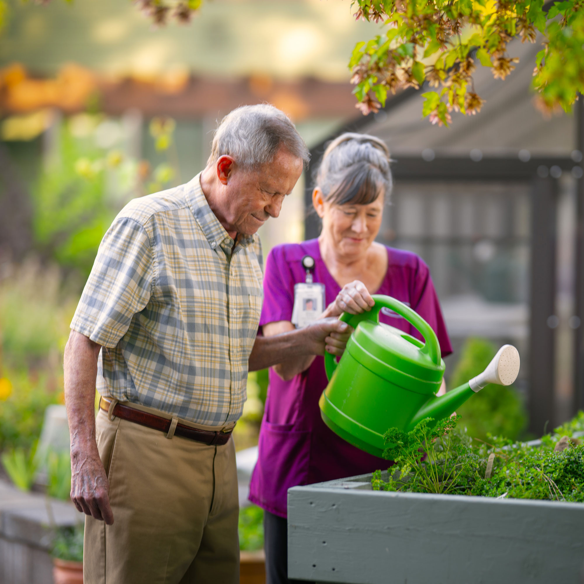 Nurse and resident watering flowers.